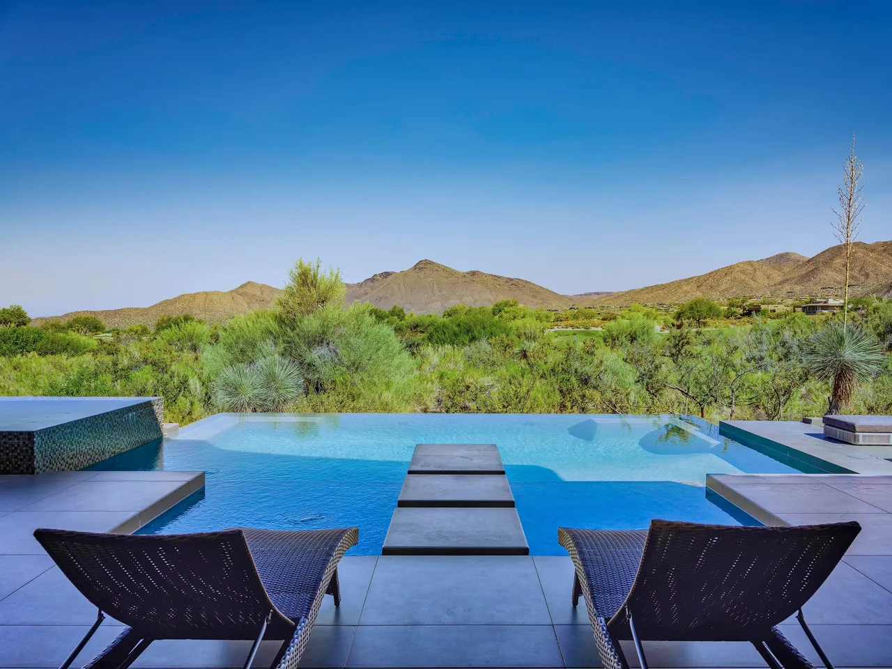 A pool with chairs and a mountain view