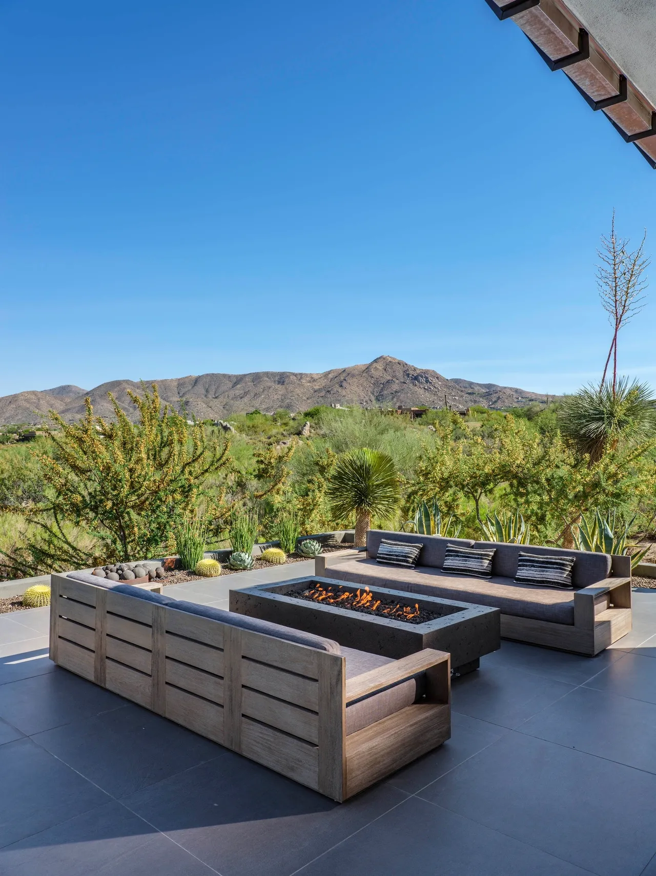 A patio with a fire pit and wooden furniture.