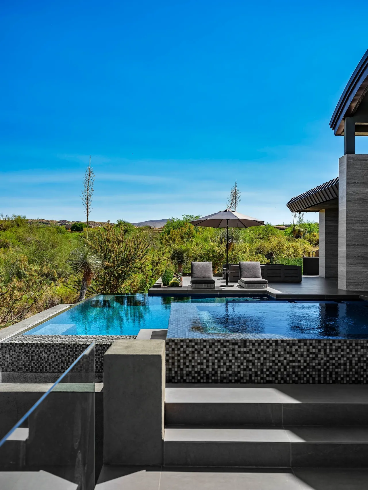 A pool with an outdoor seating area and a large swimming pool.