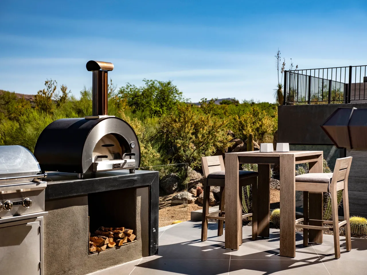 A bbq grill and table in the middle of an outdoor patio.