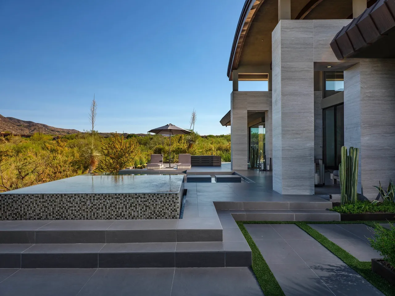 A large patio with a fountain and grass.