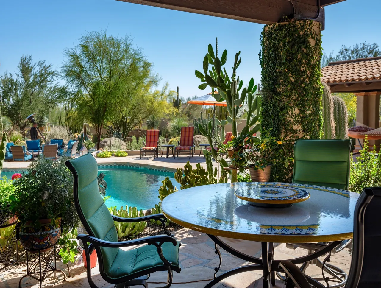 A patio with a table and chairs next to the pool.