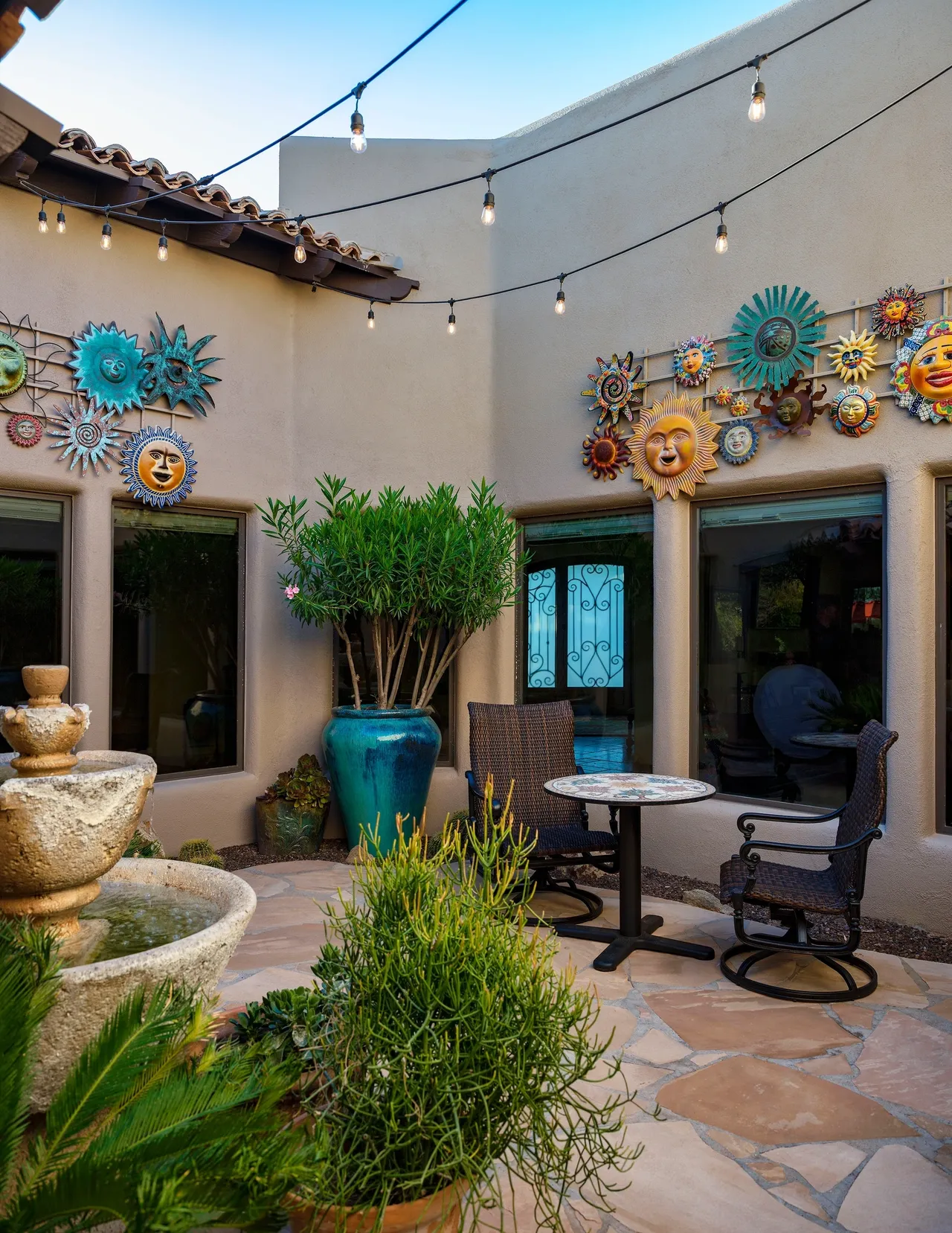 A patio with tables, chairs and a fountain.