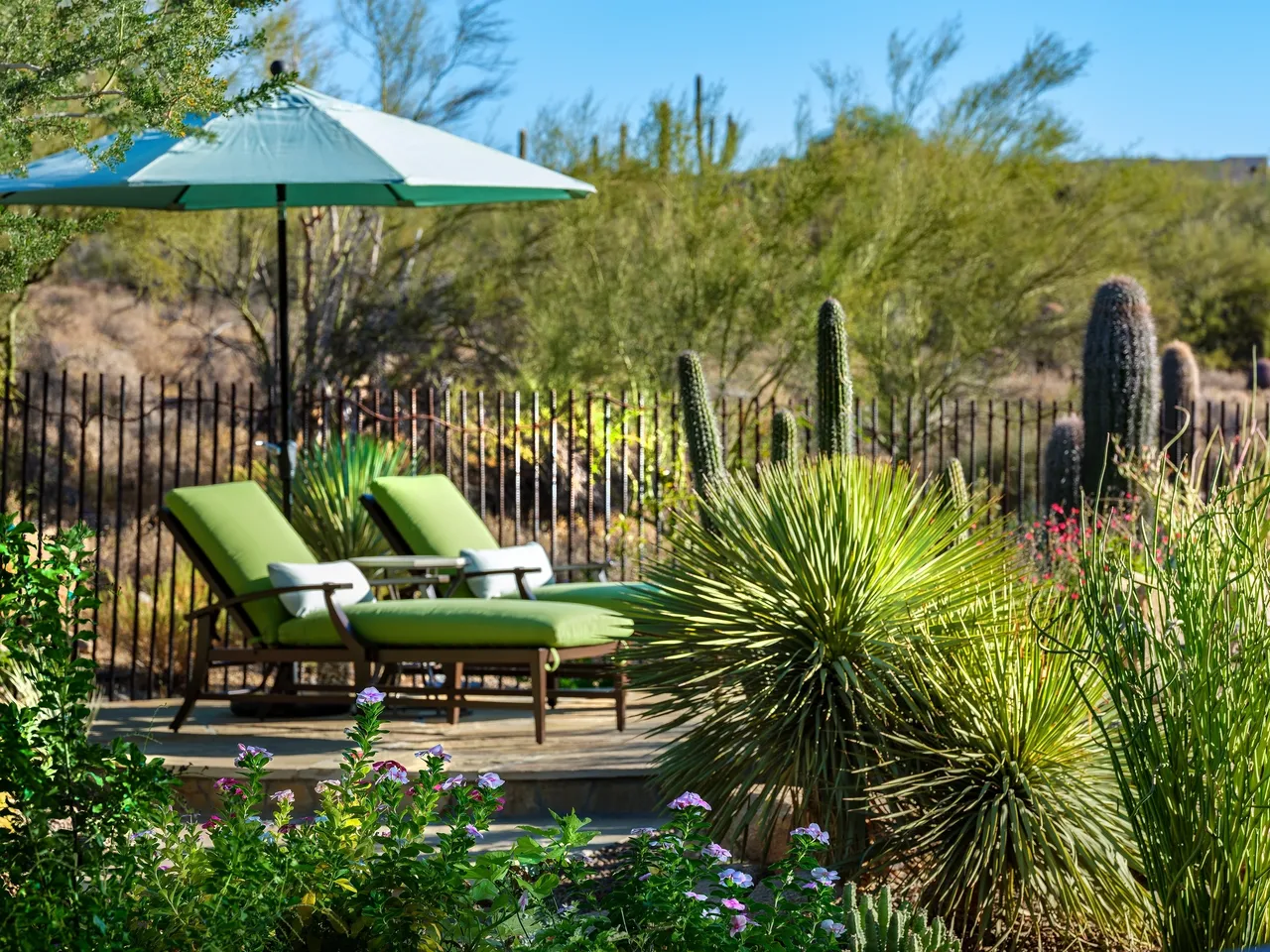 A patio with two green chairs and an umbrella.