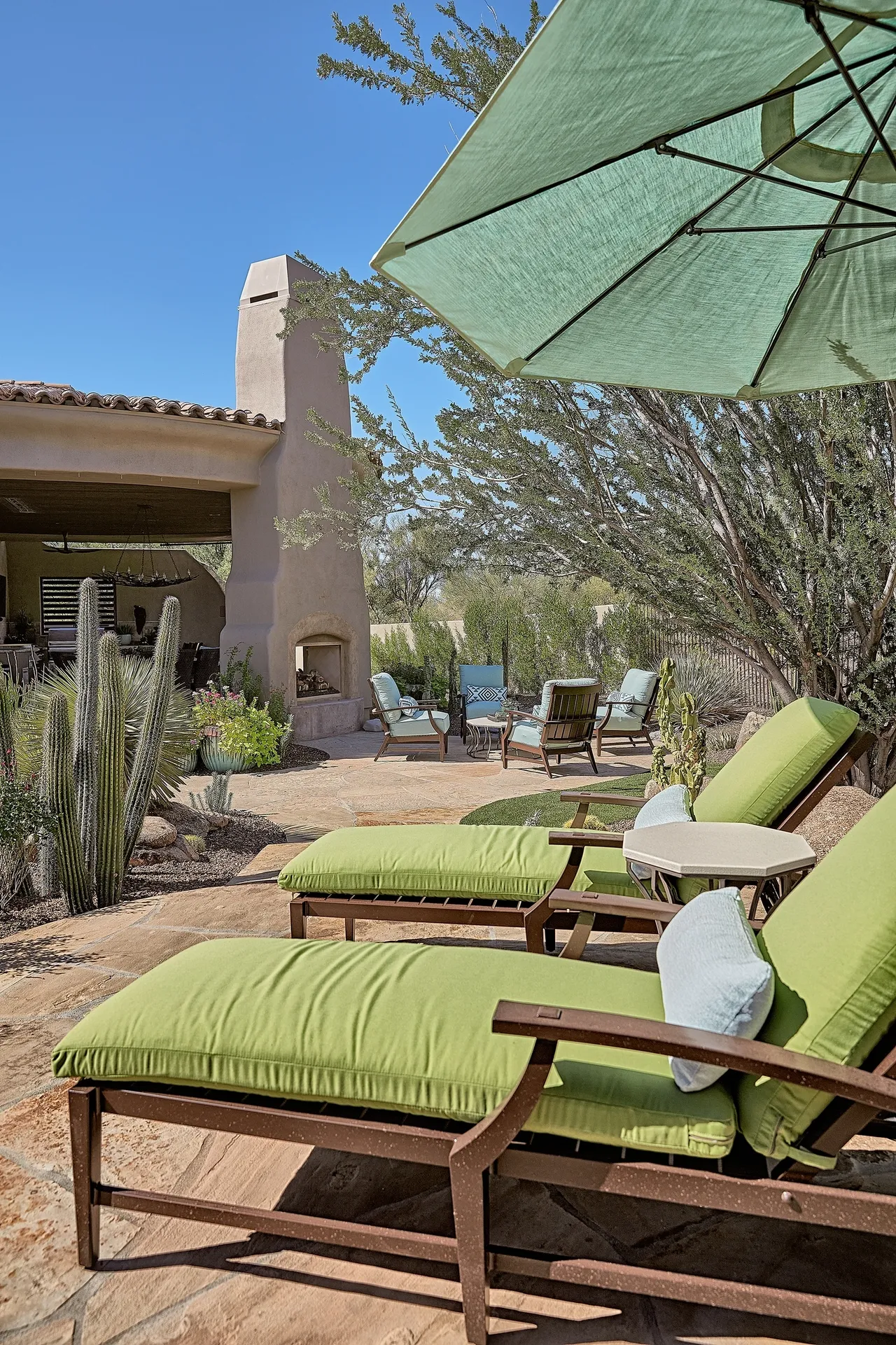 A patio with green chairs and an umbrella.