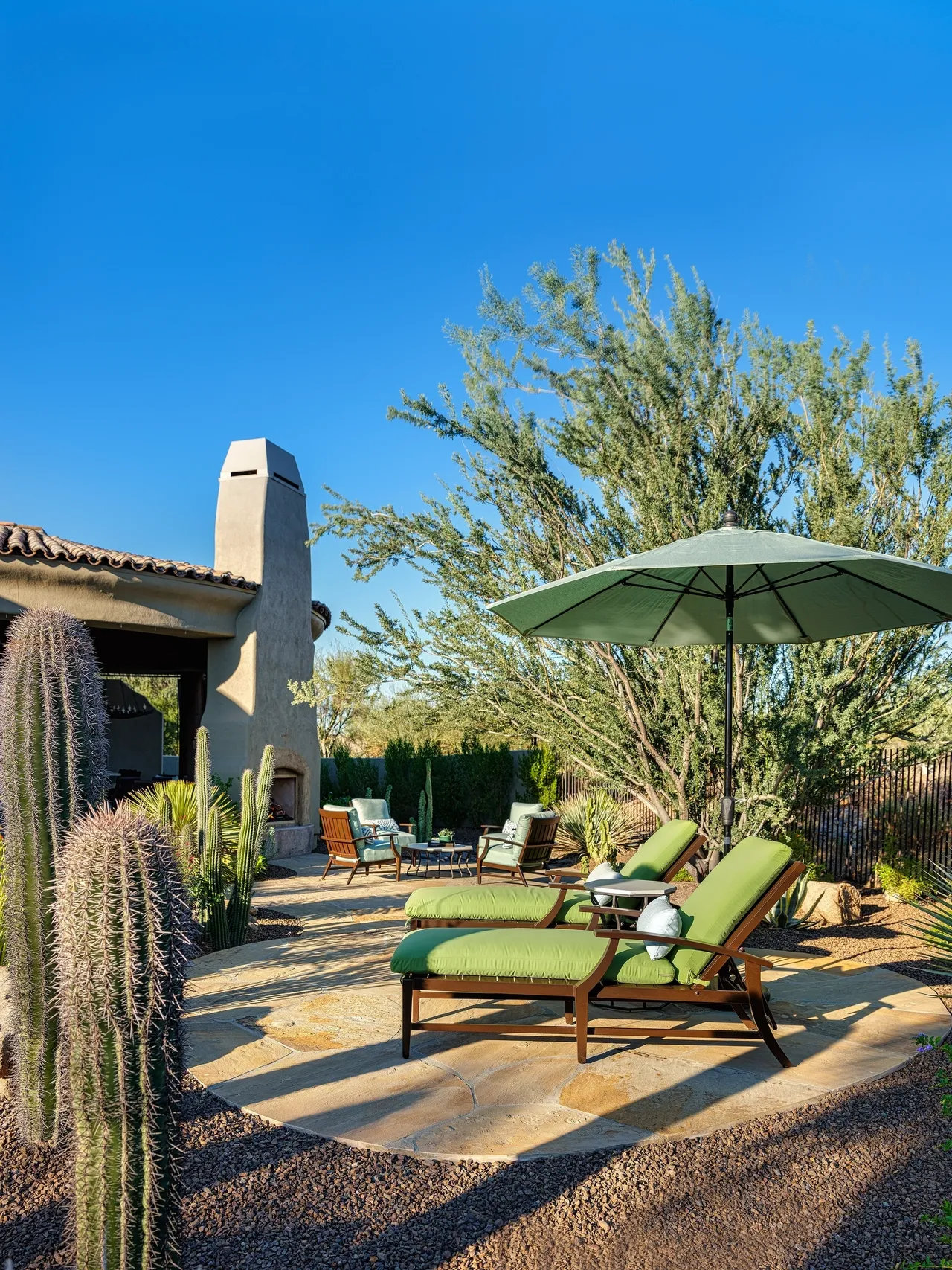 A patio with chairs and an umbrella in the middle of it.