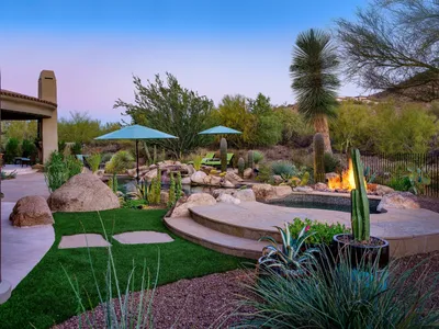 A backyard with fire pit, patio umbrellas and palm trees.