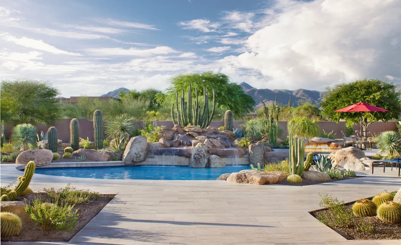 A pool with a waterfall and rocks in the background.