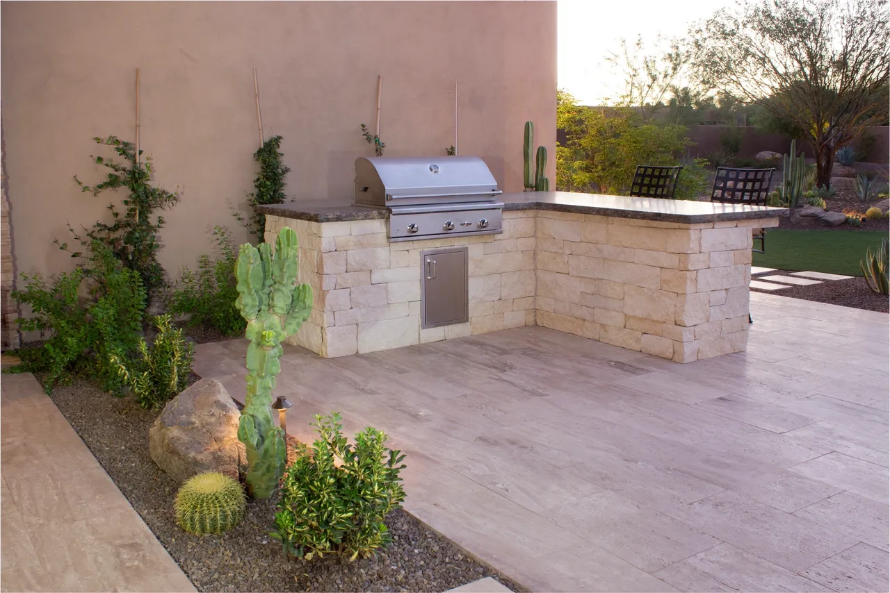 A patio with an outdoor grill and cactus.