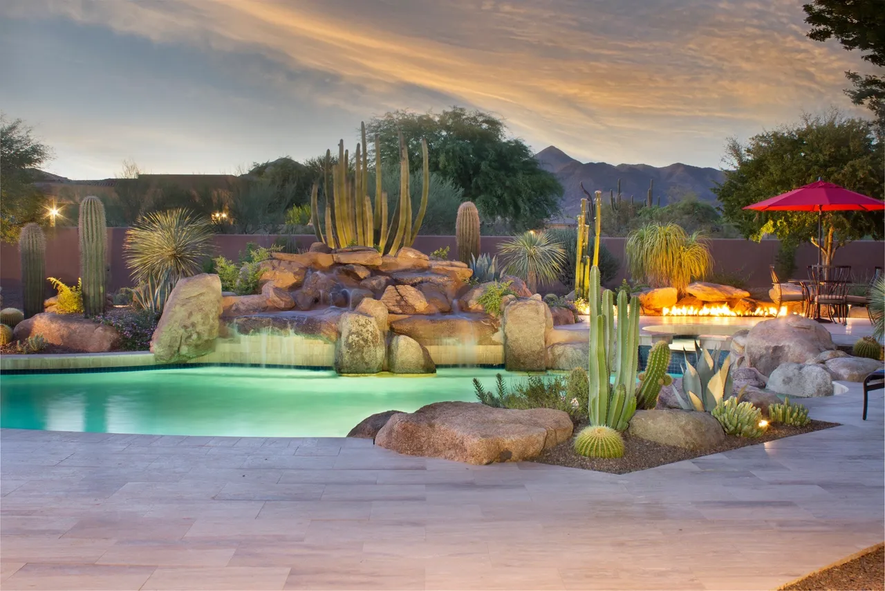 A painting of a pool with cacti and mountains in the background.