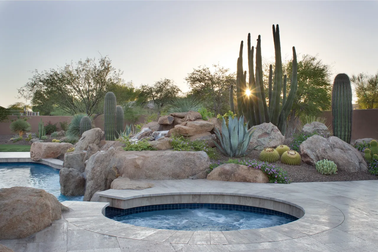 A pool with a waterfall and a rock garden.