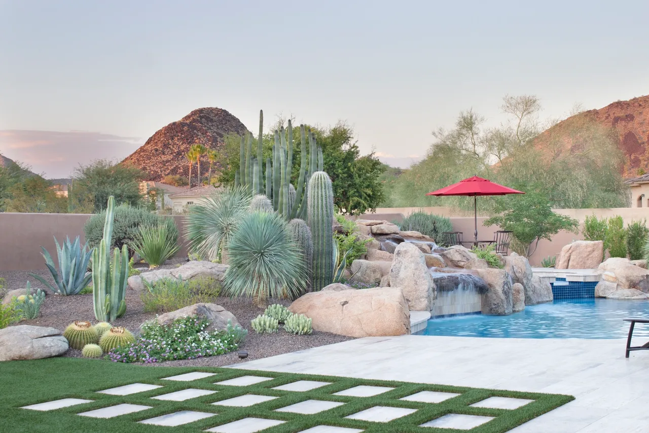 A view of a pool area with a waterfall and a gazebo.