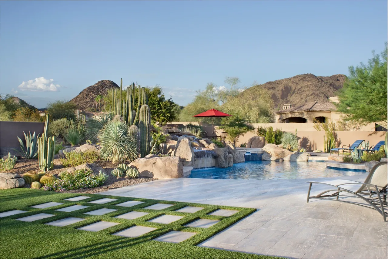 A pool with grass and rocks in the background.