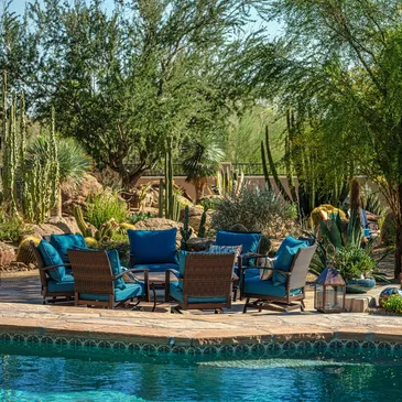 A pool with blue furniture and plants next to it.