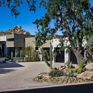 A large driveway with trees and bushes in front of it.