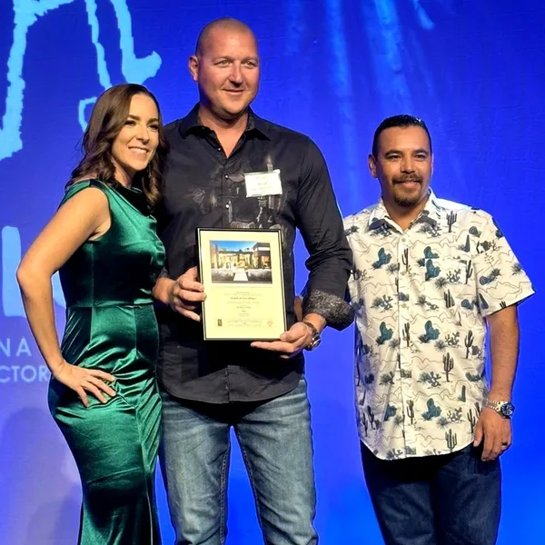 A man holding an award standing next to two women.