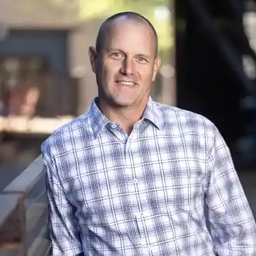 A man in plaid shirt standing outside near steps.