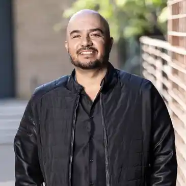 A man in black jacket standing next to a wall.