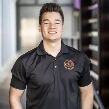 A man in black shirt standing next to a wall.