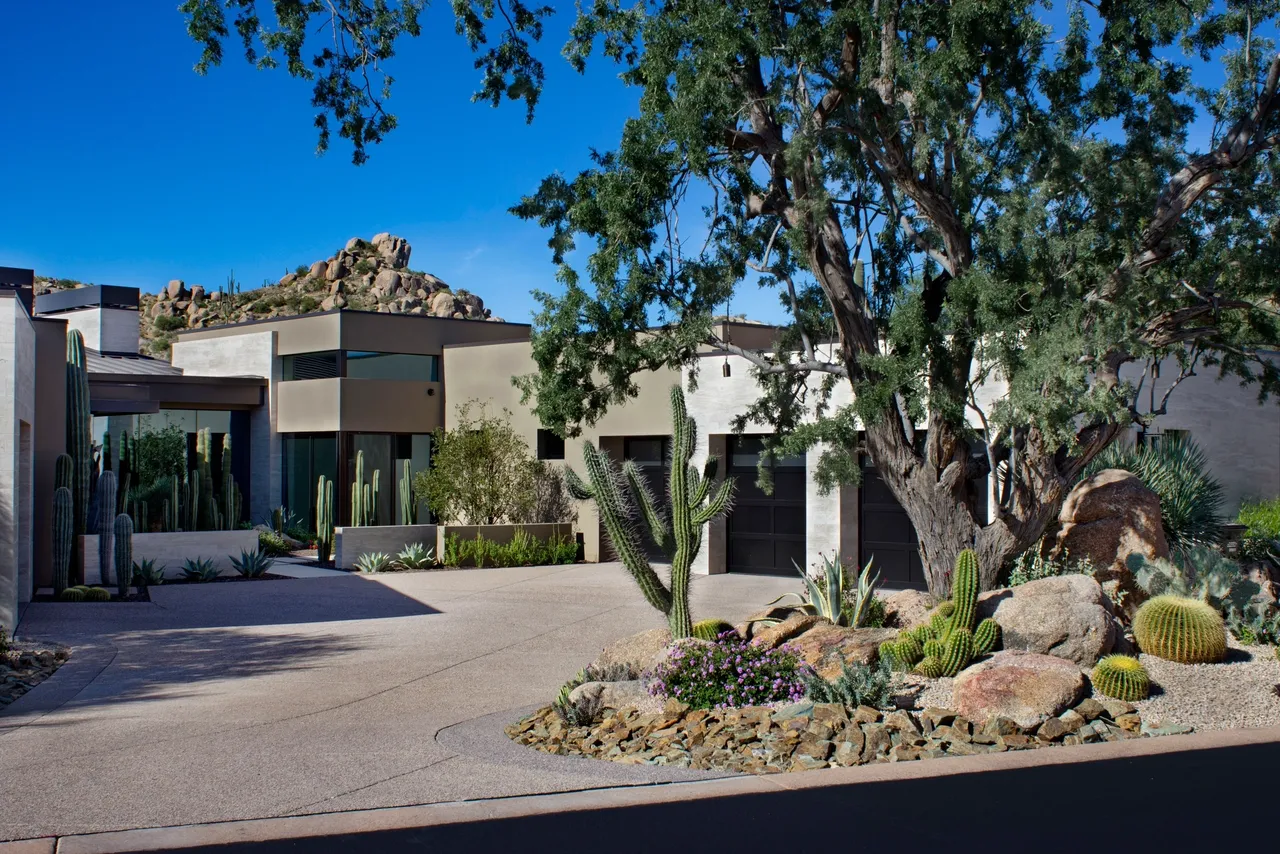 A large driveway with trees and bushes in front of it.