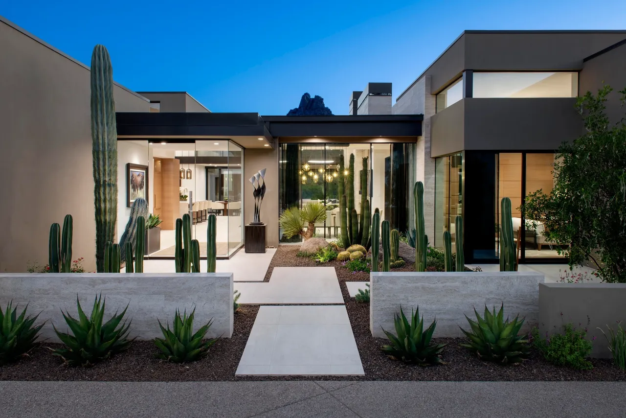 A modern house with cactus and concrete planters.