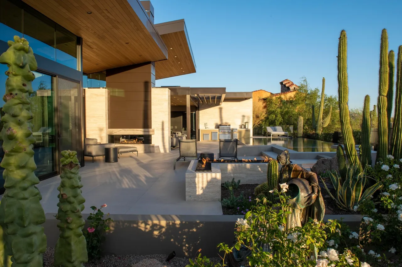 A patio with furniture and plants in the background.