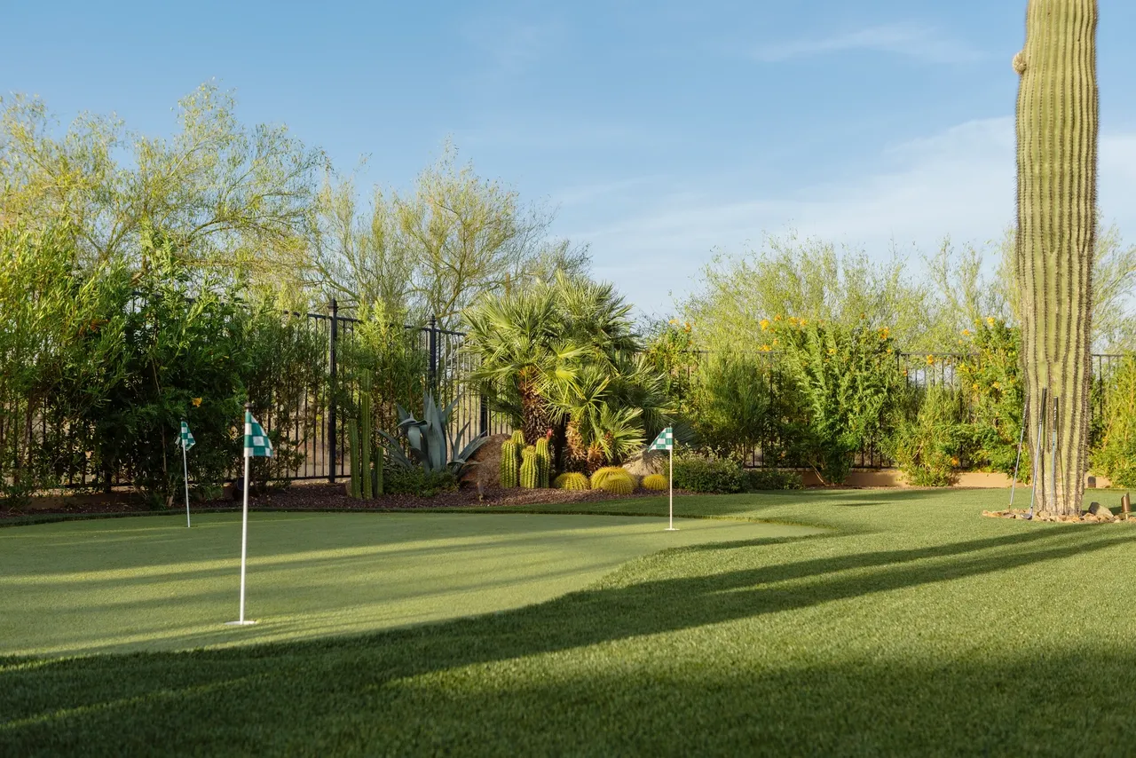 A golf course with trees and bushes in the background.