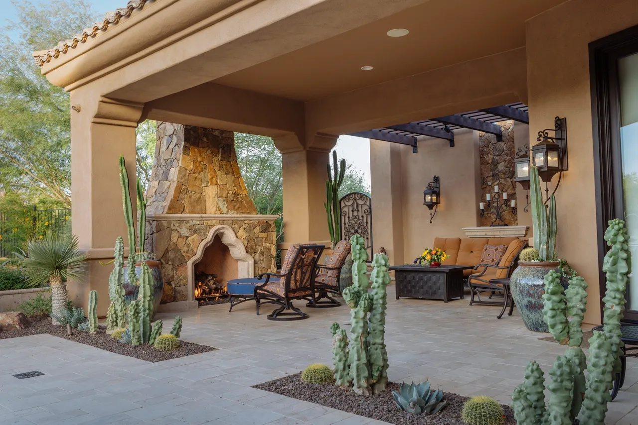 A patio with chairs, tables and a fireplace.