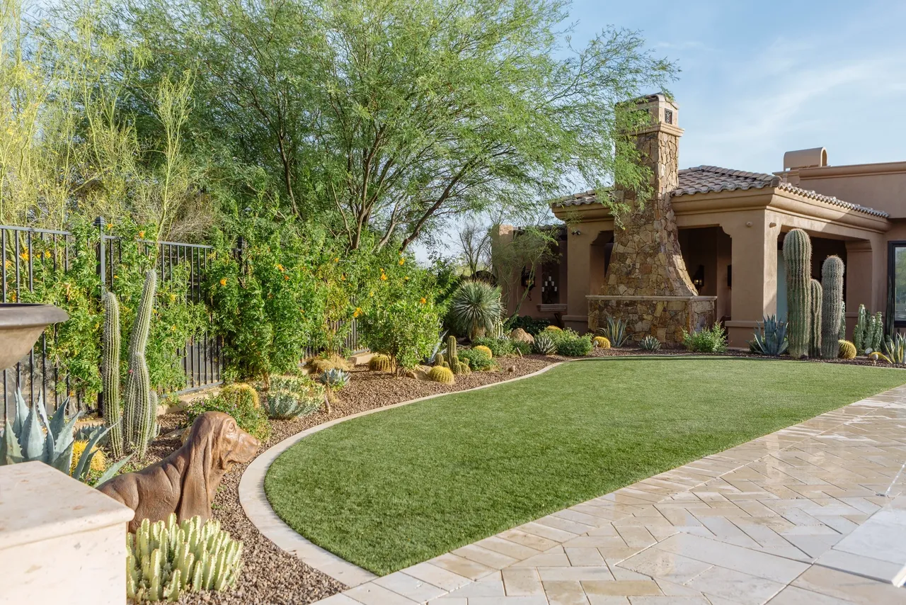 A backyard with a large lawn and a fire pit.