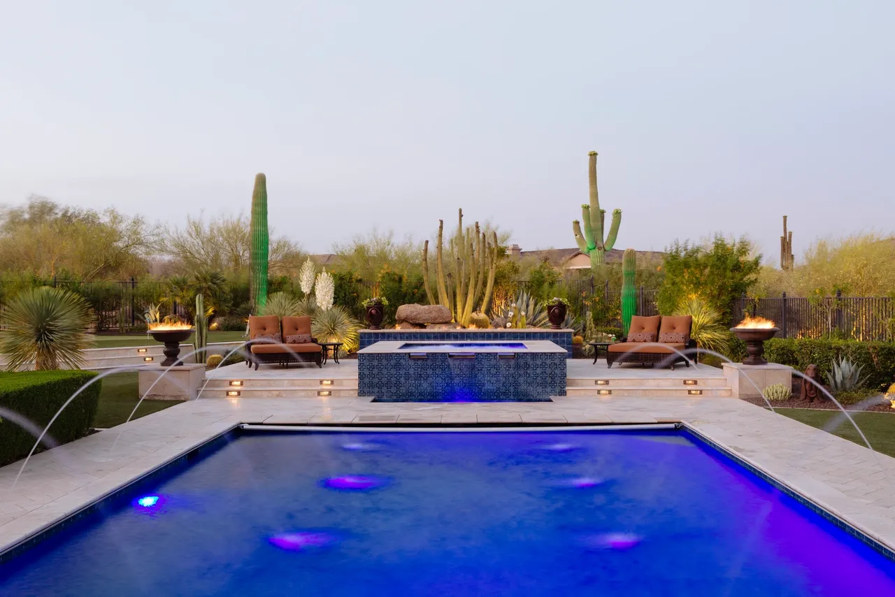 A pool with a jacuzzi and a lot of chairs