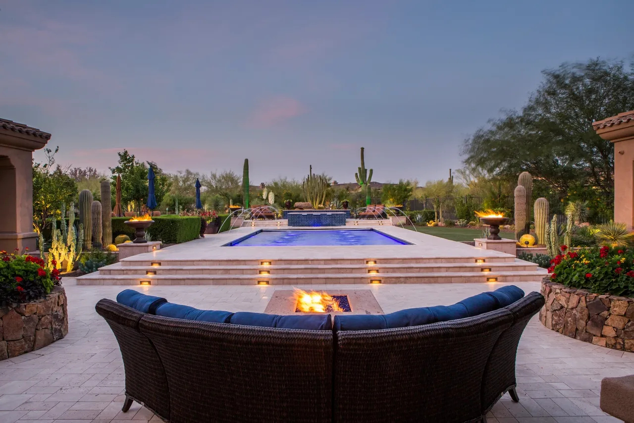 A pool with fire pits and blue couches