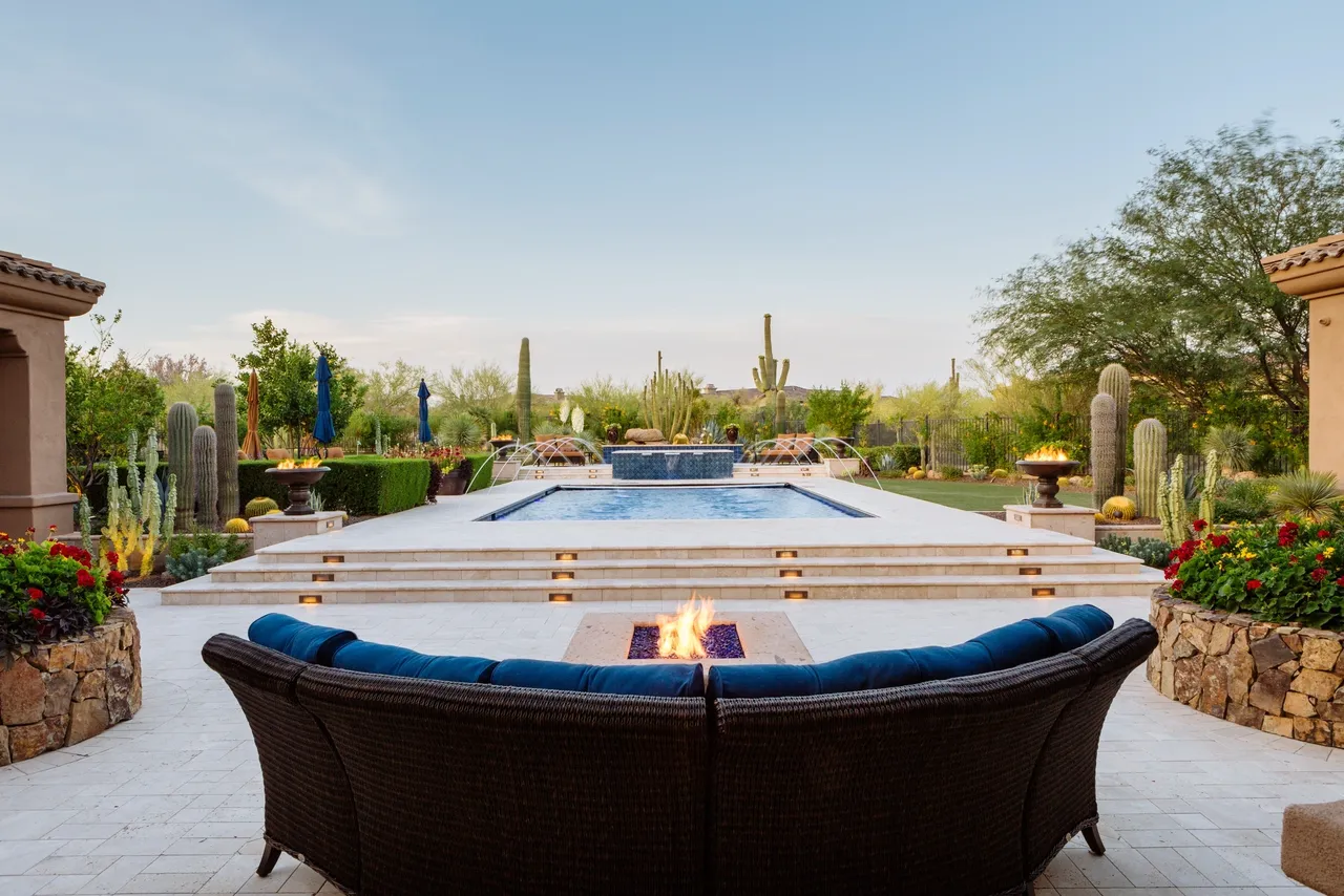 A pool with a fire pit and blue chairs