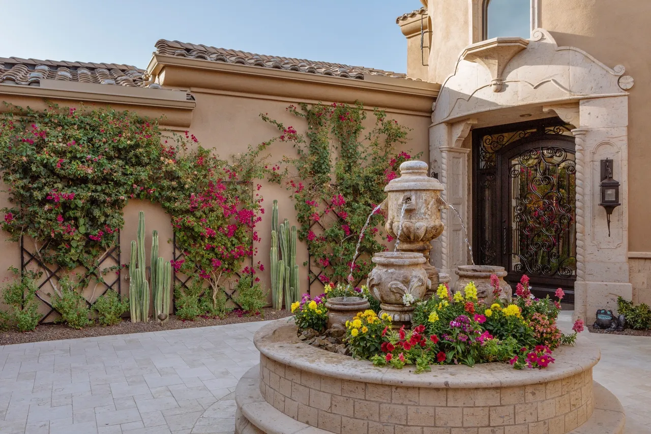 A fountain in the middle of a courtyard with flowers.