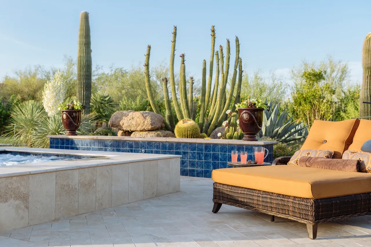 A patio with a couch and chairs in front of a pool.