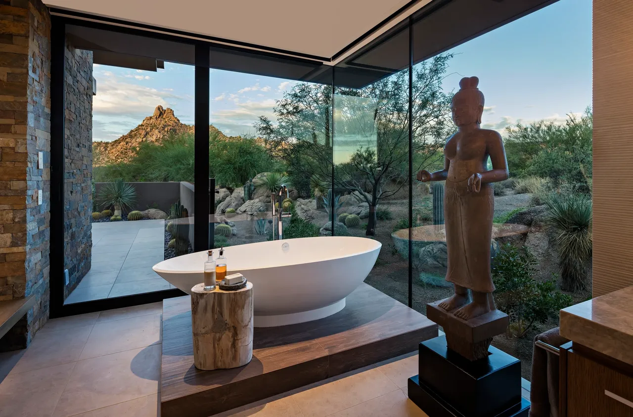 A bathroom with a statue of buddha and a tub.