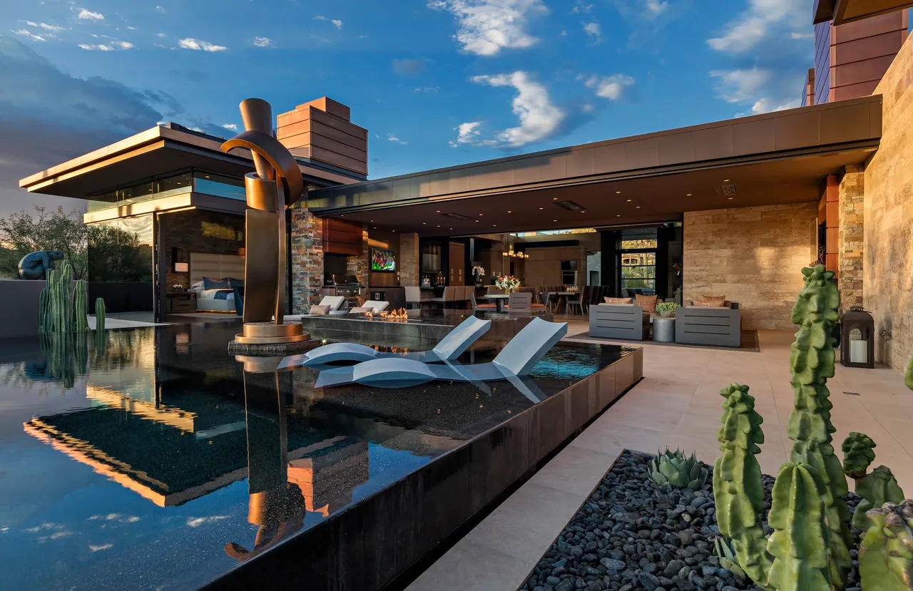 A pool with chairs and a fountain in the middle of it.