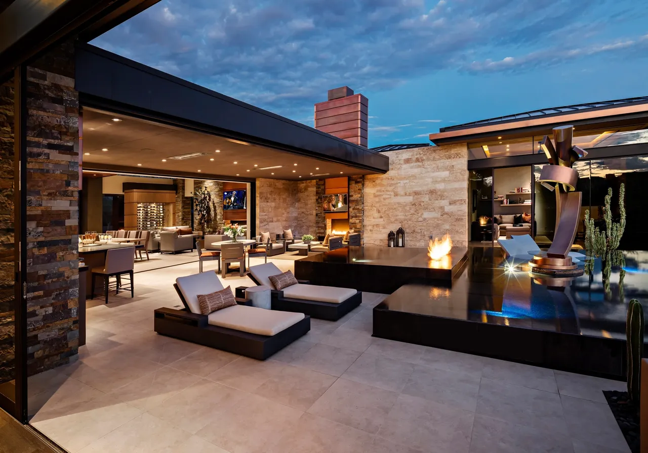 A patio with couches and chairs, fire pit and water feature.