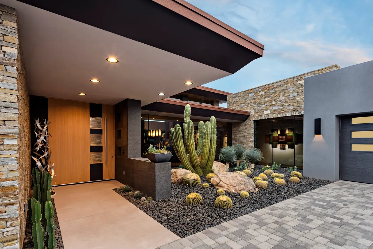 A cactus and some rocks in front of a building.