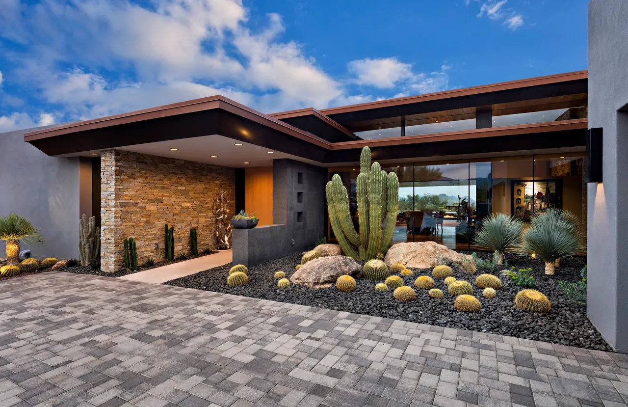 A large cactus and some rocks in front of a house.