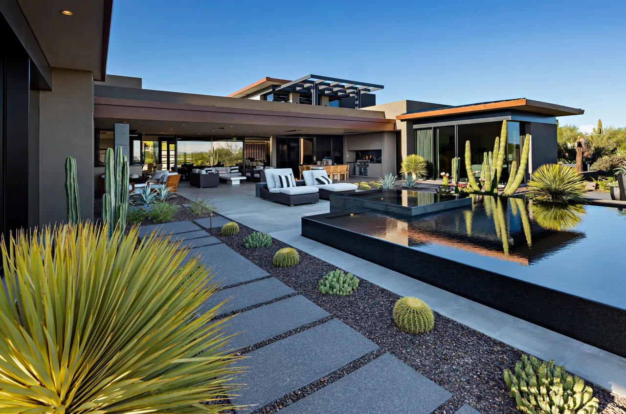 A large patio with a pool and cactus.