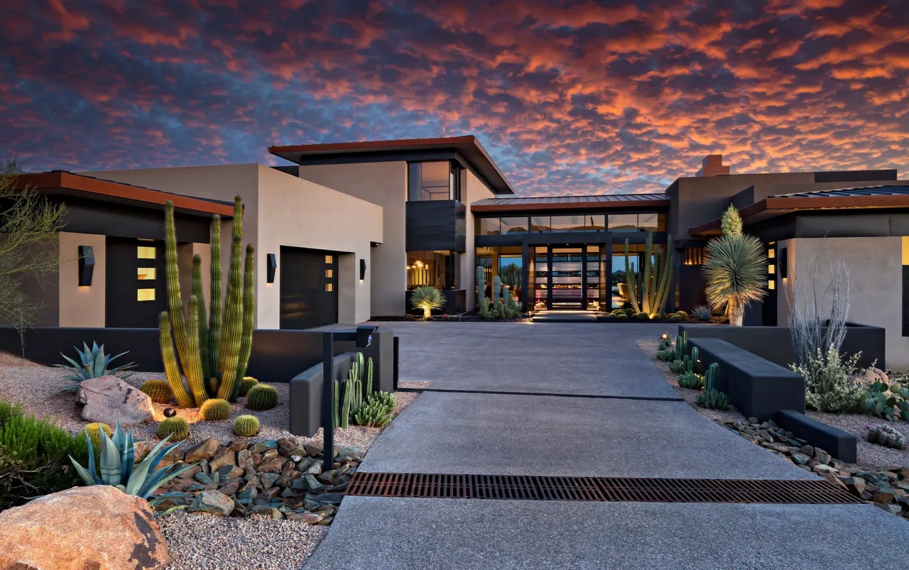 A large modern home with cactus and desert plants.