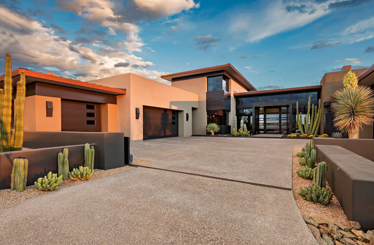 A large modern home with desert landscaping and sky.