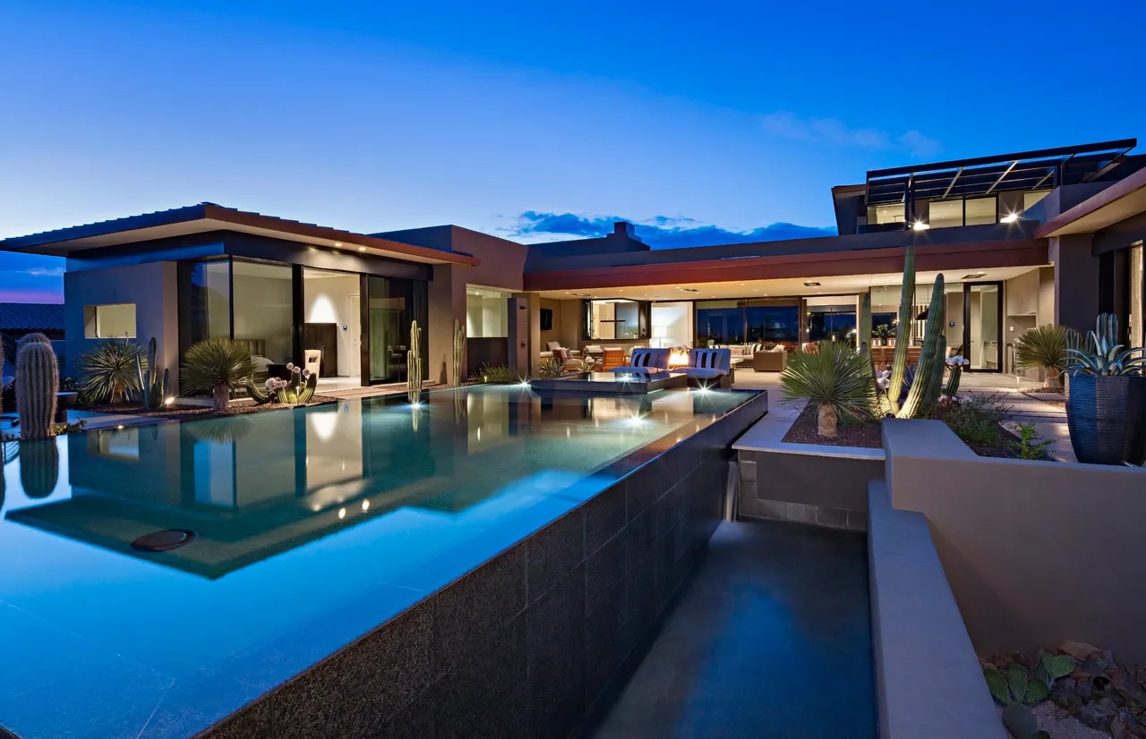 A large pool in front of a house at night.