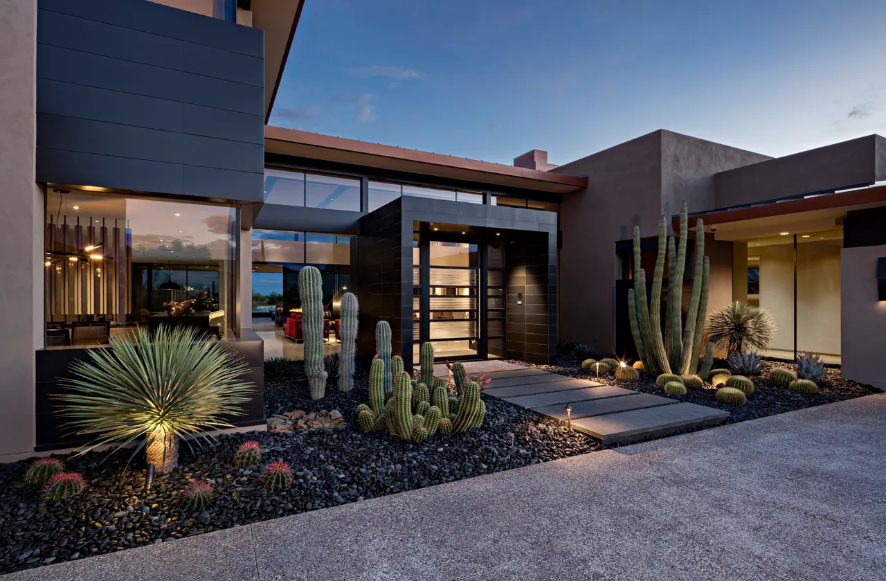 A modern house with cactus and plants in the front yard.