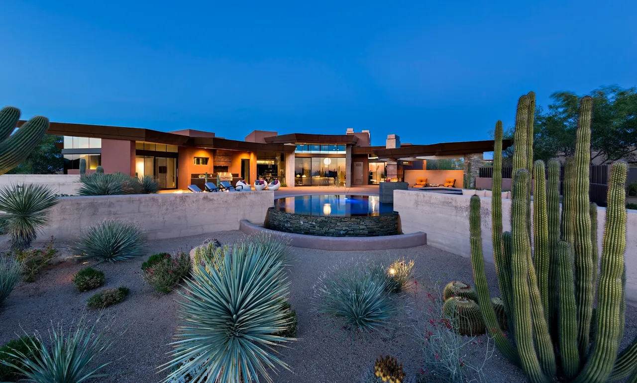 A large desert home with a pool and cactus.