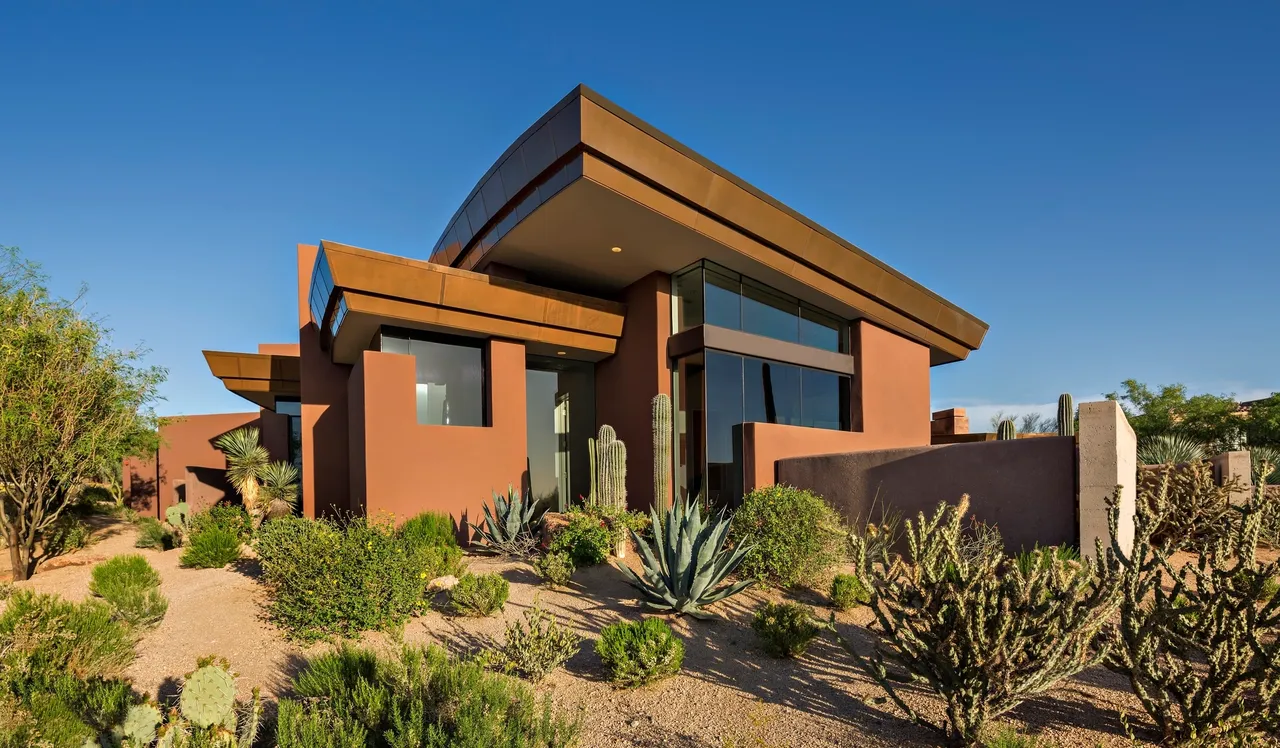 A house with a cactus and desert plants in the foreground.