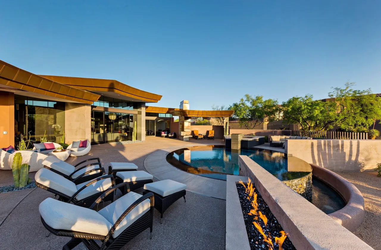 A large pool with fire pit and lounge chairs.