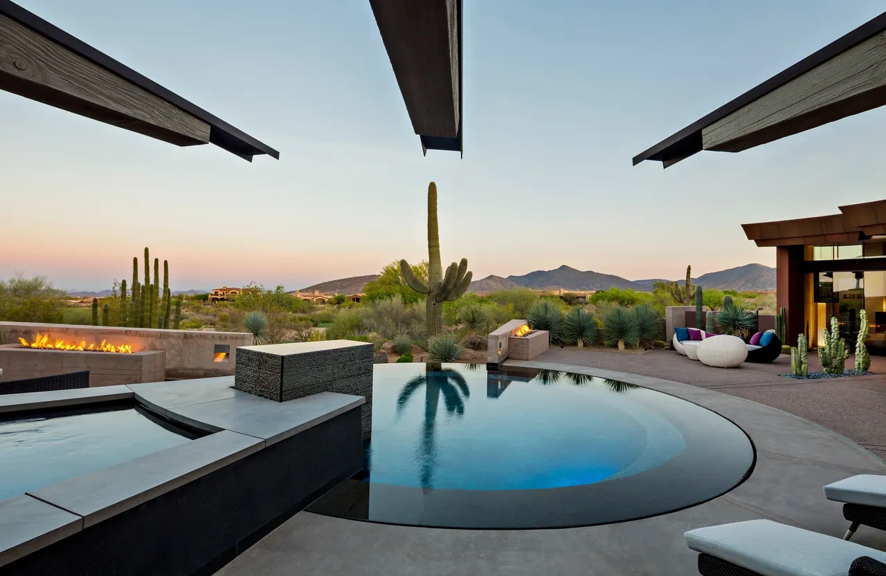 A pool with an outdoor patio and desert landscape.