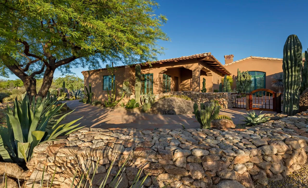 A house with a cactus and some bushes