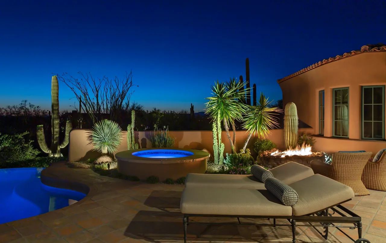 A patio with a fire pit and lounge chairs.